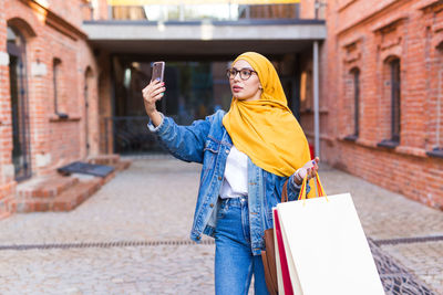 Woman holding umbrella while standing on street in city