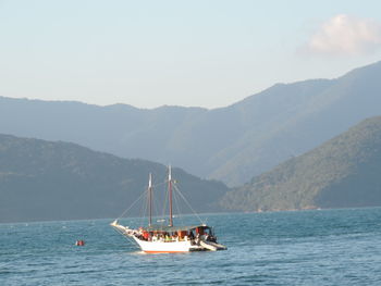 Sailboat sailing on sea against mountains