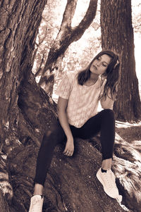 Portrait of woman sitting on tree trunk