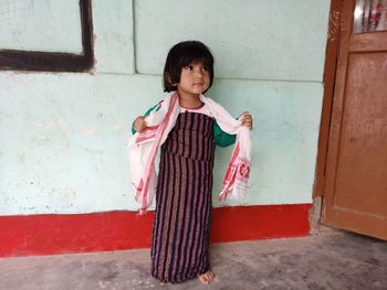 Full length of cute girl standing against wall