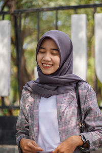 Portrait of a smiling hijab muslim female student in front of a park