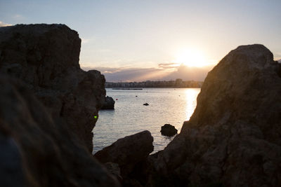 Rock formation by sea against sky during sunset