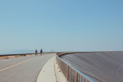 Man cycling on road against clear sky