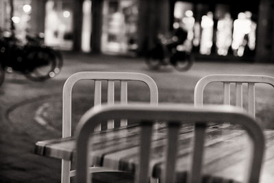 Close-up of empty bench on street in city