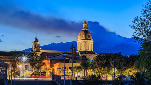 Buildings of the city of riposto with the background of the erupting volcano etna