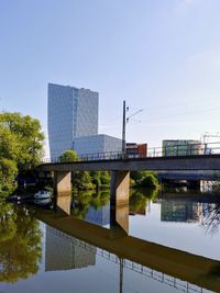 Bridge over lake against buildings in city against clear sky