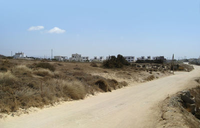 Road amidst desert land against sky