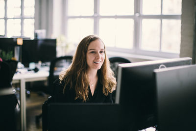 Young woman using mobile phone while sitting in office