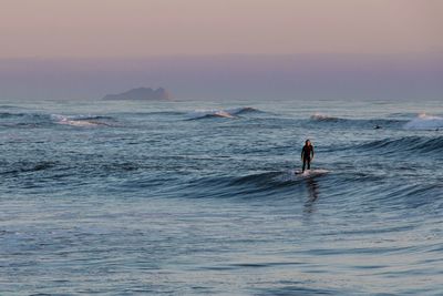 Man on sea against sky during sunset