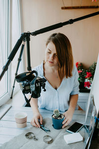 Woman photographing while sitting on table