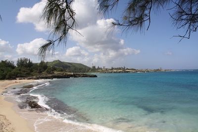 Scenic view of beach against cloudy sky