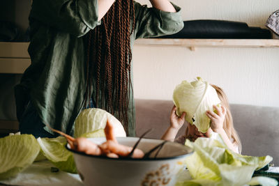 Happy vegan family mom and baby daughter cooking together and having fun on kitchen. family cooking