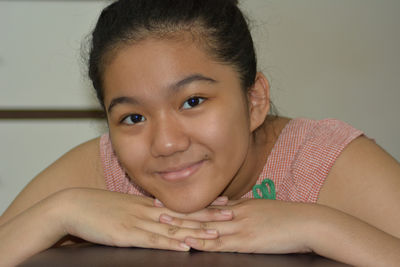 Close-up portrait of a smiling young woman against wall at home