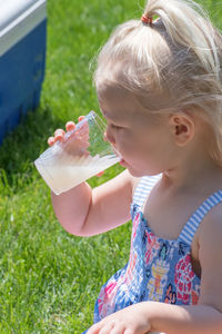 Close-up of cute girl drinking juice in park during sunny day