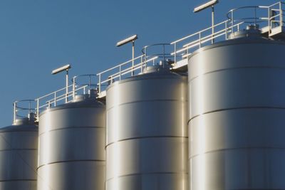 Low angle view of industry against clear blue sky