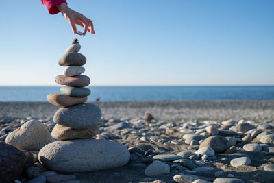 Hand puts a stone on tower on beach. house by sea. background for real estate advertising. 