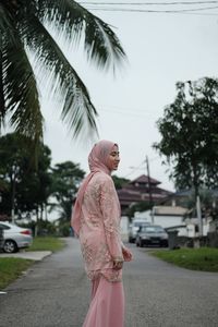 Woman standing on road against trees