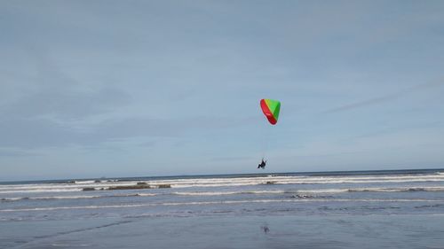 Paraglider paragliding over sea against sky