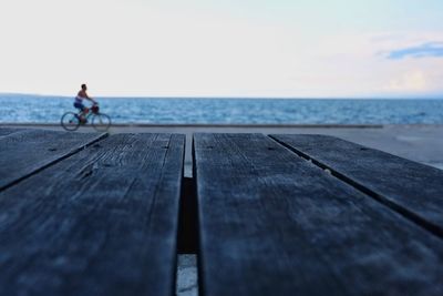 Side view of man riding bicycle by sea against clear sky