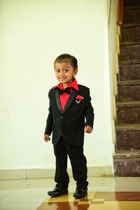 Portrait of cute boy standing against wall