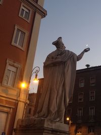 Low angle view of statue against illuminated city at night