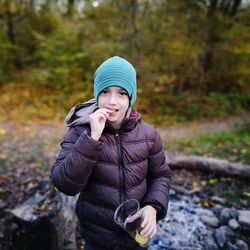 Portrait of boy eating chips while standing on field