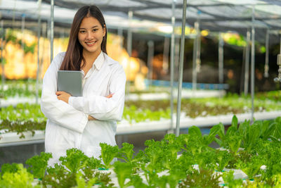 Portrait of young woman standing in greenhouse