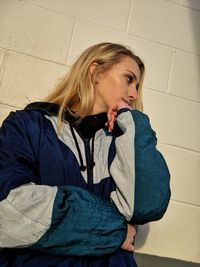 Portrait of young woman sitting against wall