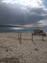 Deck chairs on beach against sky