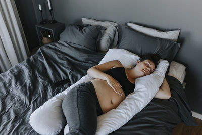 Pregnant woman sleeping on pregnancy pillow on bed