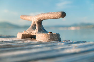 Close-up of rusty metal on table at beach against sky