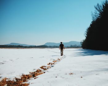 Man standing on snow covered landscape against clear sky