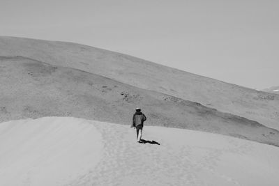 Rear view of man on sand dune in desert