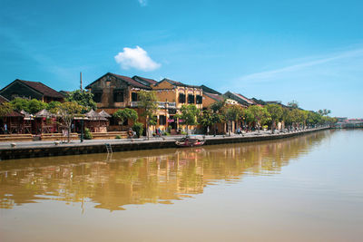 Houses by lake and buildings against sky