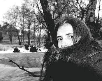 Close-up portrait of young woman with bare tree