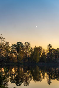 Reflection of silhouette trees in lake against sky during sunset