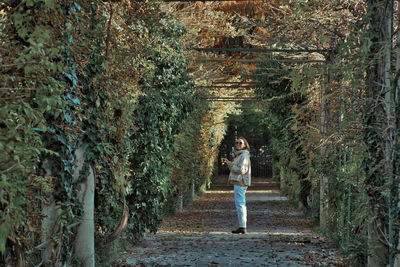 Woman walking on footpath amidst trees in forest