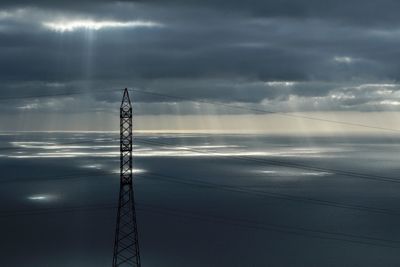 Electricity pylon against cloudy sky