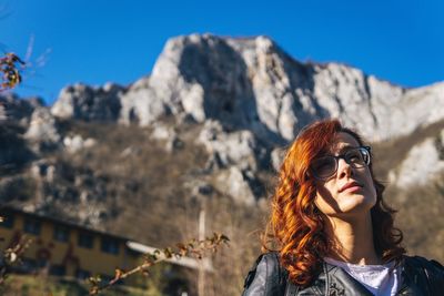Portrait of young woman in sunglasses against mountains