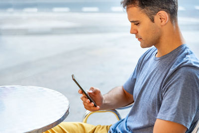 Young man using mobile phone while sitting outdoors