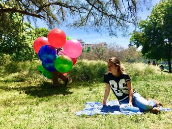 Rear view of woman sitting on balloons at field