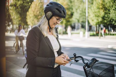 Businesswoman wearing cycling helmet using smart phone