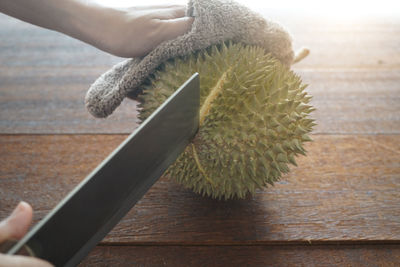 Close-up of hand holding fruit on table