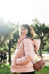 Portrait of smiling young woman standing against trees