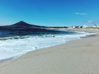 Scenic view of beach against blue sky