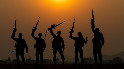 Silhouette people on field against sky during sunset