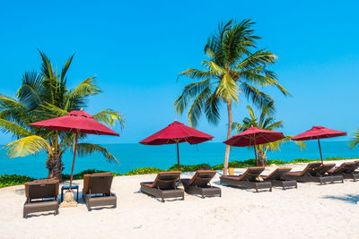 Lounge chairs and parasols on beach against clear blue sky