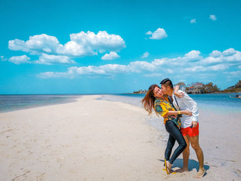 Woman with umbrella on beach against sky