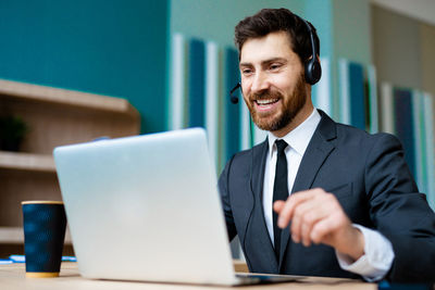 Portrait of businessman using laptop at office