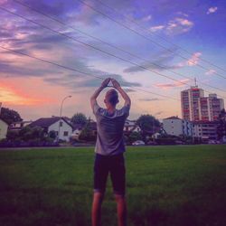 Full length of man with arms raised against sky